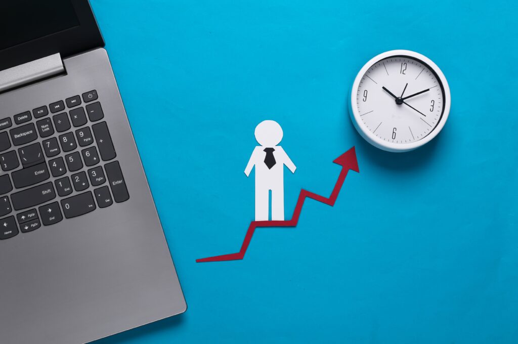 Benefits of computerized appointment scheduling: A laptop, business papers, and a growth arrow symbolizing financial and social success, representing the efficiency and progress achievable with computerized appointment scheduling.