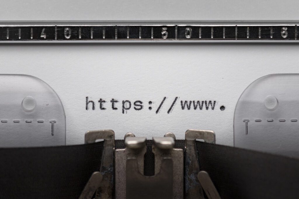 Close-up of a vintage typewriter typing a web address, highlighting why a domain is important for online presence.