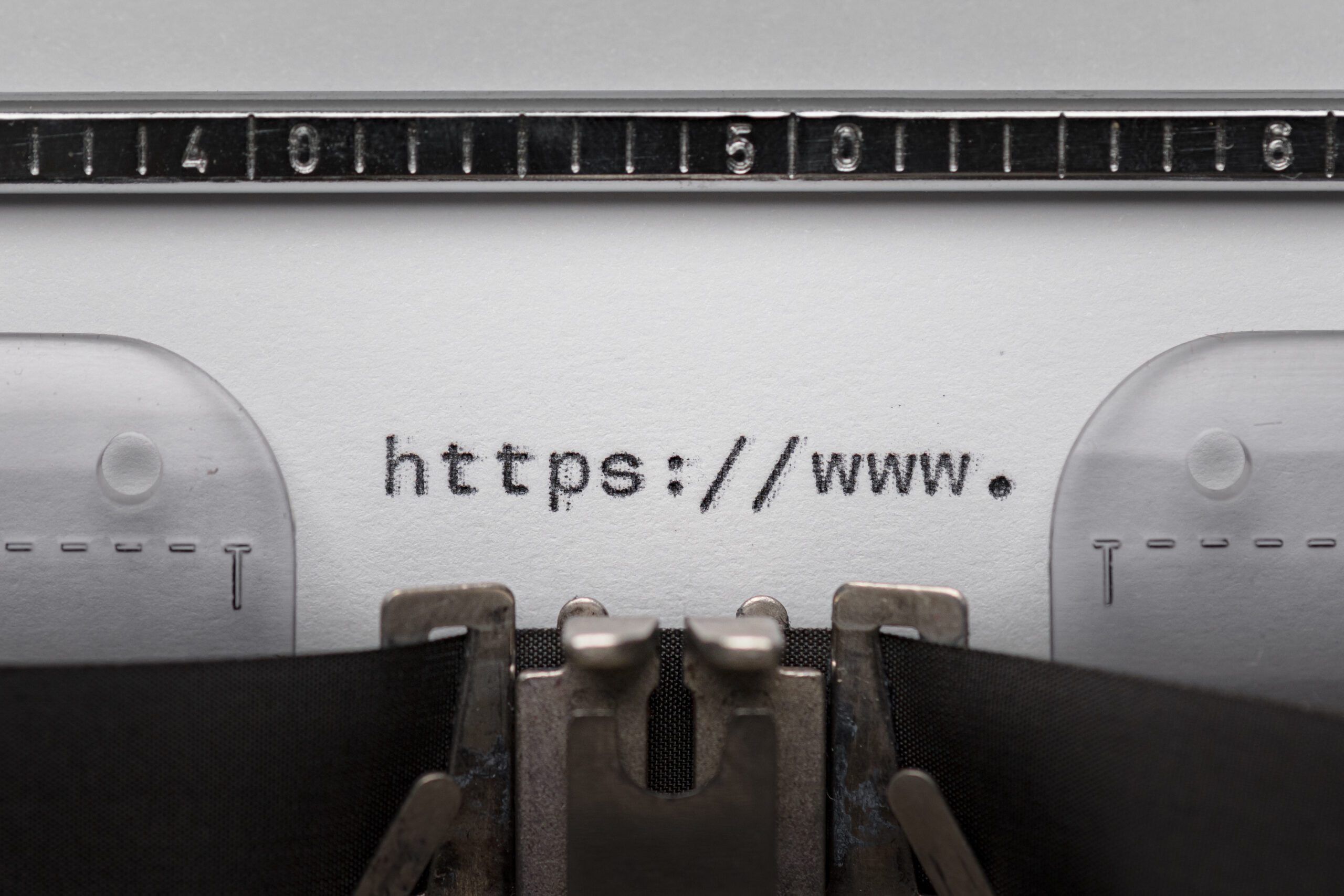 Close-up of a vintage typewriter typing a web address, highlighting why a domain is important for online presence.